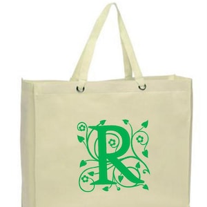 Puede incluir: Una bolsa de lona blanca con asas verdes y un diseño floral verde con la letra "R" en el centro.