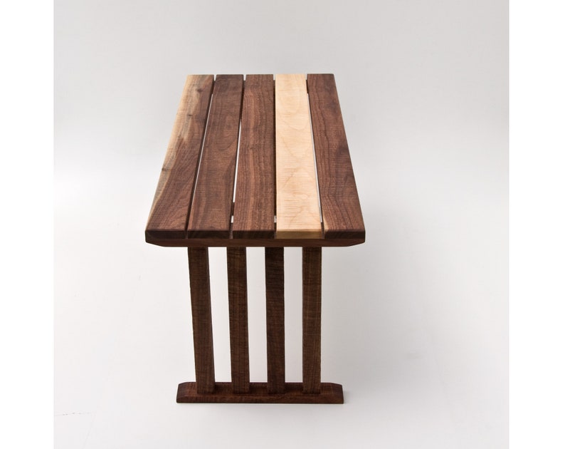 May include: A wooden table with a walnut and maple top. The table has a simple, modern design with a rectangular top and four legs.