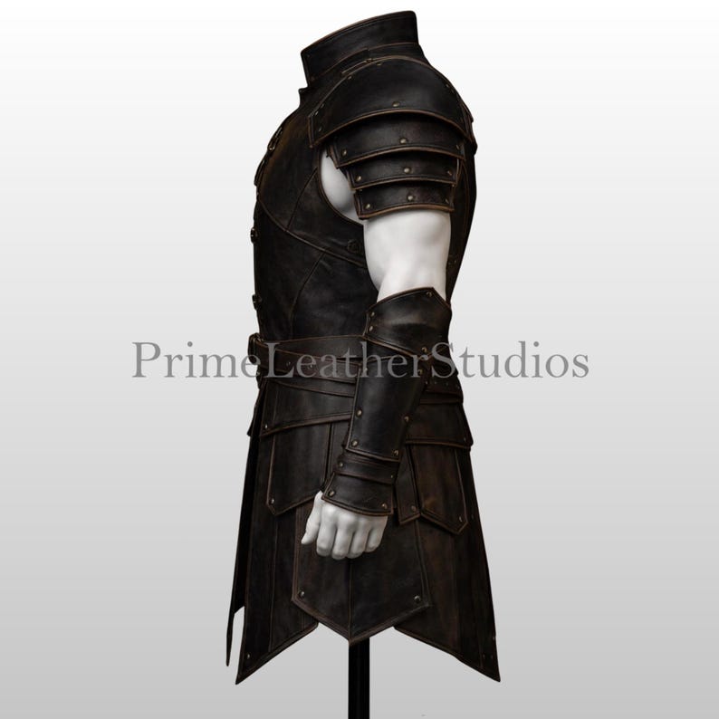 Pode incluir: Uma armadura de couro castanho escuro com ombreiras, protetores de bra&ccedil;o e uma saia. A armadura tem um acabamento envelhecido e &eacute; detalhada com rebites e um cinto. O texto "Prime Leather Studios" &eacute; vis&iacute;vel.