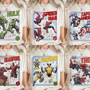 May include: Cream-coloured t-shirts showcasing Marvel superheroes: Hulk, Spider-Man, Captain America, Deadpool, Wolverine, and Thor. Each shirt has a character image, name, and signature within a framed design. The shirts are worn by a person.