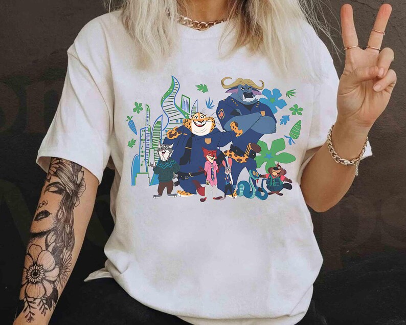 May include: White t-shirt with a vibrant graphic of Zootopia characters. The design showcases animal characters in police uniforms against a cityscape. The tee has short sleeves and is made of a soft material.
