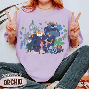 May include: Lilac Comfort Colors t-shirt with a cartoon graphic of animal characters. The graphic features characters in police uniforms and civilian clothes. The text "COMFORT COLOR" and "ORCHID" are printed on the bottom of the shirt. The shirt is a relaxed fit.