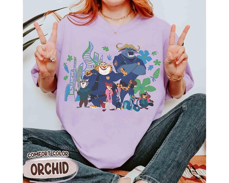 May include: Lilac Comfort Colors t-shirt with a cartoon graphic of animal characters. The graphic features characters in police uniforms and civilian clothes. The text "COMFORT COLOR" and "ORCHID" are printed on the bottom of the shirt. The shirt is a relaxed fit.