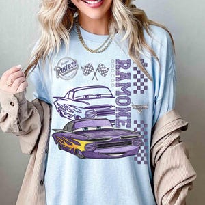 May include: Light blue long-sleeve shirt featuring a graphic of the character Ramone from the movie Cars. The design includes two cartoon cars, the name "Ramone", checkered flags, and the Rust-eze logo. The shirt has a relaxed fit.