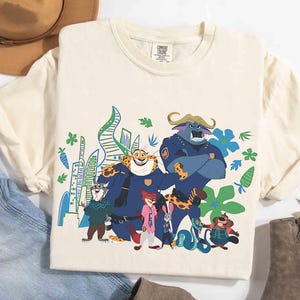May include: Cream-coloured t-shirt with a vibrant graphic of characters from the animated film "Zootropolis." The design showcases animal characters in police uniforms and civilian clothes, set against a cityscape. The shirt has short sleeves and a crew neck.