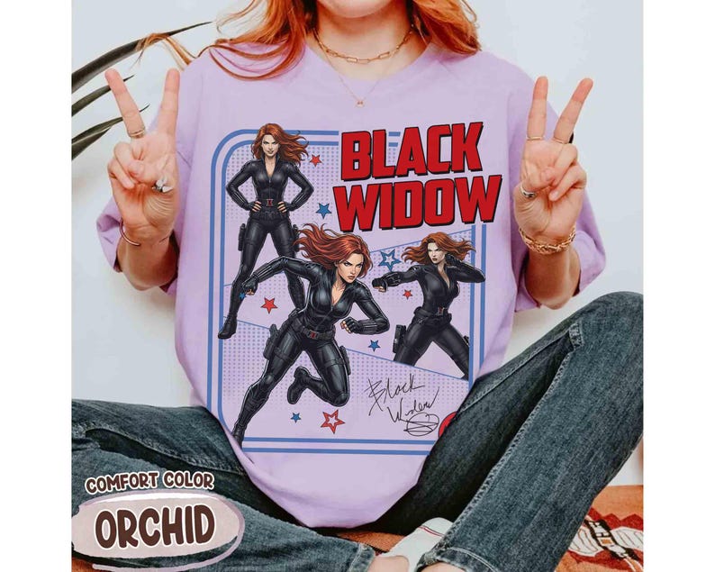 May include: Orchid-coloured t-shirt with a retro Black Widow graphic. The design features the text "BLACK WIDOW" in red and white, illustrations of the character, and her signature. The shirt is labelled "COMFORT COLOR".