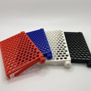 May include: A set of four rectangular panels featuring a repeating hexagonal grid pattern. Each panel is a different solid color: red, blue, white, and black. Each piece includes a small hexagonal protrusion on one side and a support leg.
