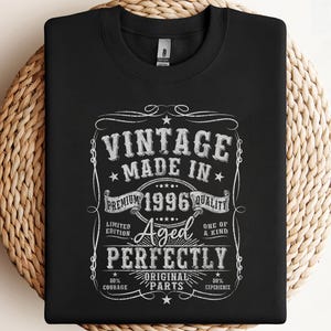 May include: Black crew neck sweatshirt with a vintage-style graphic. The graphic reads "VINTAGE MADE IN 1996 QUALITY" with additional text: "Aged Perfectly", "Original Parts", "Limited Edition", "One of a Kind", "50% Courage", and "50% Experience".