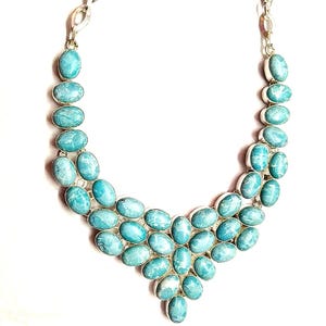 May include: A silver necklace featuring oval-shaped, light blue gemstones. The gemstones are set in a silver metal and arranged in a cascading design. The necklace has a chain closure.