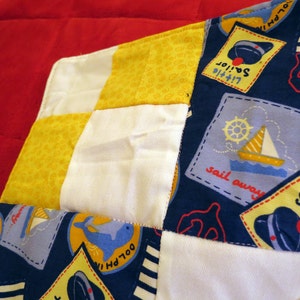 Dolphin Cove Little Sailor baby quilt in nautical navy, yellow, white and red image 1