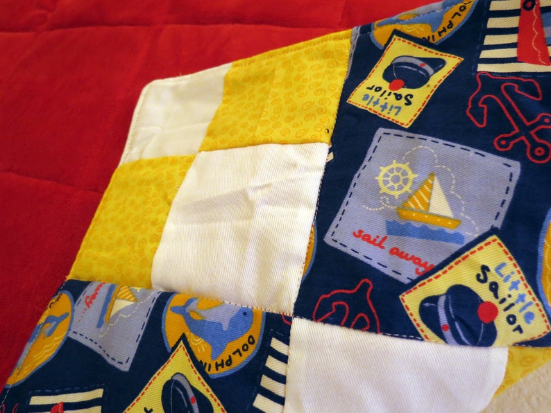 Dolphin Cove Little Sailor baby quilt in nautical navy, yellow, white and red image 1