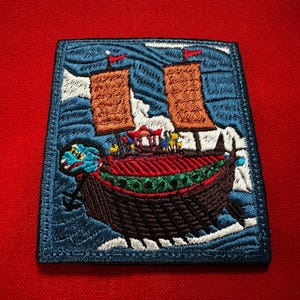 May include: Embroidered patch showing a traditional Asian ship on blue waves. The ship has brown sails, a red roof, and a dragon figurehead. The patch is bordered in blue and set against a red background.