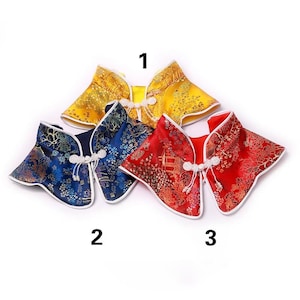 Puede incluir: Se muestran cinco chaquetas chinas tradicionales en amarillo, azul y rojo. Las chaquetas presentan patrones detallados y ribetes blancos. Cada chaqueta tiene un diseño único y se abrocha con un cierre de nudo blanco.