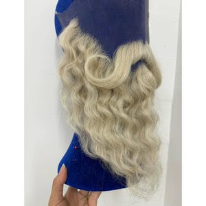 Peut inclure: Une barbe en dentelle avec des cheveux longs, ondulés et blond clair fixés sur une base en maille bleue transparente. Les poils du visage présentent un motif ondulé naturel, conçu pour être appliqué sur le menton et la mâchoire.