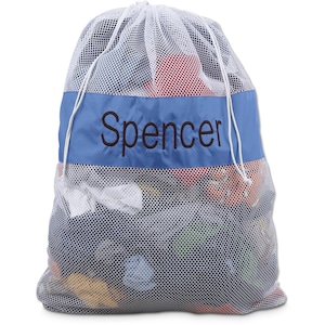 May include: White mesh laundry bag with a blue stripe and the name "Spencer" embroidered in brown. The bag is filled with colorful clothes.