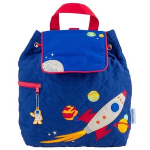 May include: A blue quilted backpack with a rocket, planets, and stars embroidered on it. The backpack has a flap with a moon and stars embroidered on it. The backpack has a zipper closure and a small astronaut keychain.