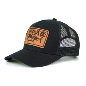 May include: Black trucker hat with a mesh back and a curved brim. The front features a rectangular patch with the text "ANGEL AB" and a shark illustration in brown tones. The hat is designed for sun protection and casual wear.