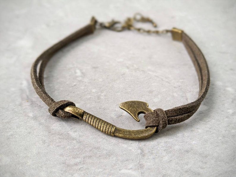 May include: A brown leather cord bracelet with a bronze fish hook charm.