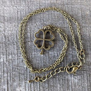 May include: A gold-toned necklace with a four-leaf clover pendant. The necklace is made of a delicate chain and has a lobster clasp.