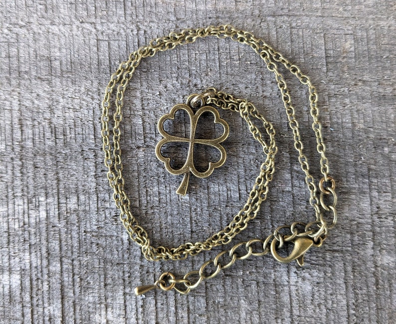 May include: A gold-toned necklace with a four-leaf clover pendant. The necklace is made of a delicate chain and has a lobster clasp.