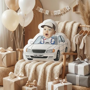 May include: A decorative pillow shaped like a white car with a baby's face in the driver's seat. The pillow has a license plate that reads "WILLIAM". The scene includes balloons, wrapped gifts, and a "BABY SHOWER" banner.