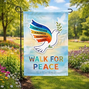 Puede incluir: Una bandera de jardín con una paloma que lleva una rama de olivo y la frase "Walk for Peace". La paloma tiene una pancarta arcoíris con las palabras "Hope, Compassion, Kindness, Harmony, Love".