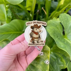Funny Cowboy Opossum Badge Reel – “Hold On Partner I’m Overstimulated” ID Holder, Cute Neurodivergent Humor Clip, Gift for Nurses & Teachers