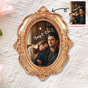Puede incluir: Un marco de fotos ovalado dorado y ornamentado con una fotografía de una pareja. El marco tiene un diseño vintage detallado. La foto está personalizada con los nombres "Amy & Leo" en escritura cursiva. Una imagen más pequeña con el texto "CUSTOM PHOTO" está en la parte superior derecha.
