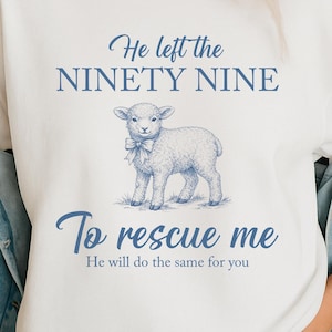 Könnte beinhalten: Weißes T-Shirt mit blauem Text und einer Lamm-Illustration. Der Text lautet "He left the NINETY NINE To rescue me He will do the same for you". Das Lamm trägt eine blaue Schleife.