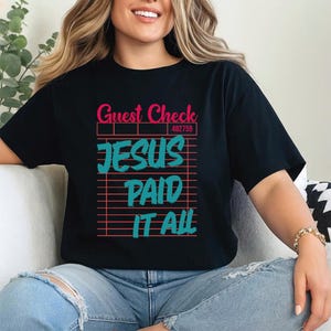 Könnte beinhalten: Schwarzes T-Shirt mit den Worten "Guest Check" in Pink und "JESUS PAID IT ALL" in Türkis. Der Text ist wie ein Kassenbon gestaltet. Das T-Shirt wird von einer Person getragen.