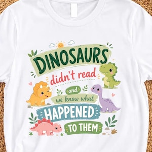 Könnte beinhalten: Ein weißes T-Shirt mit einer bunten Grafik und dem Text "DINOSAURS didn't read and we know what HAPPENED TO THEM". Das Design zeigt Illustrationen eines gelben Triceratops, eines grünen T-Rex, eines violetten Langhals-Dinosauriers und eines rosa Stegosaurus.
