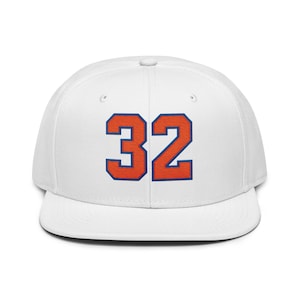 May include: A white baseball cap with a flat peak. The cap displays the number "32" in orange with a blue outline on the front. A classic, casual style.