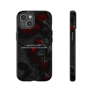 K&ouml;nnte beinhalten: Eine schwarze Smartphone-H&uuml;lle mit einem dunklen, stimmungsvollen Blumenmuster aus tiefroten Rosen auf anthrazitfarbenem Hintergrund. Der Text MEADOWS, BABY. OUR LAST NAME IS MEADOWS. ist mittig in Wei&szlig; aufgedruckt. Die H&uuml;lle hat eine Doppelkamera-Aussparung.