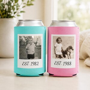 May include: Two foam can coolers, one turquoise and one pink, each featuring a white square frame containing a black and white vintage photograph. The turquoise cooler displays a child and the text EST. 1982, while the pink cooler shows a child with a toy horse and the text EST. 1988.