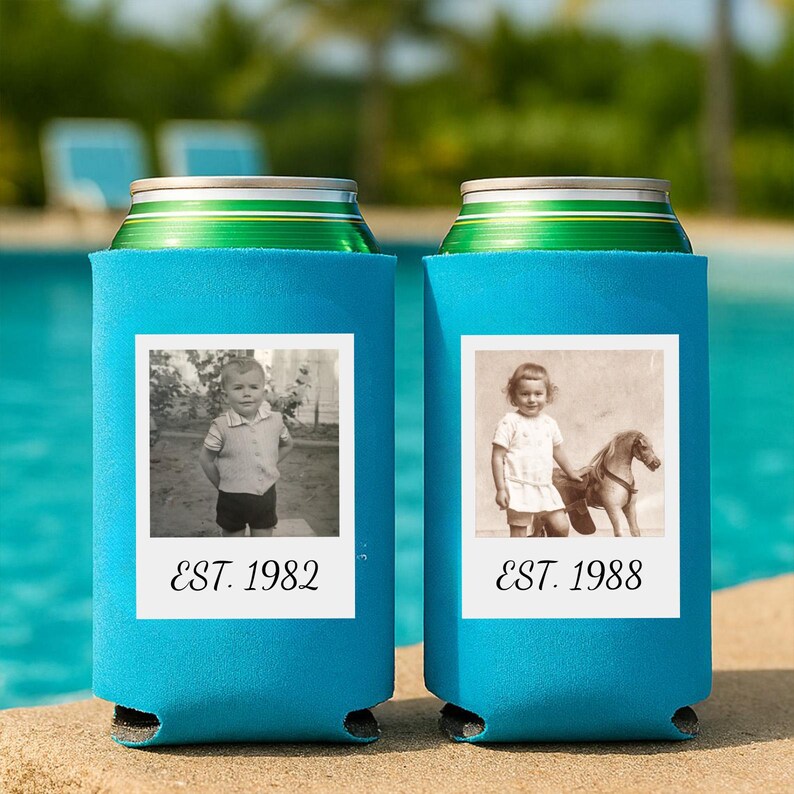 May include: Two bright blue foam can coolers, each featuring a white square frame containing a black and white vintage photograph. The left cooler displays a child and the text EST. 1982, while the right cooler shows a child with a toy horse and EST. 1988.