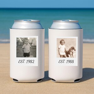 May include: Two white foam can coolers featuring personalized black and white photographs. The left cooler displays a child with the text EST. 1982. The right cooler shows a child with a toy horse and the text EST. 1988. Both are cylindrical.