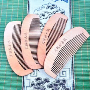 May include: Four wooden combs with fine teeth are arranged on a green and white patterned surface. Each comb is a light brown color and has the text "Natural Walnut Wood" printed on it. The combs are angled towards the right.