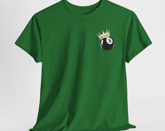 Puede incluir: Una camiseta verde con un diseño de bola ocho negra con una corona dorada. El número ocho es visible en la bola. La camiseta está hecha de un material suave.