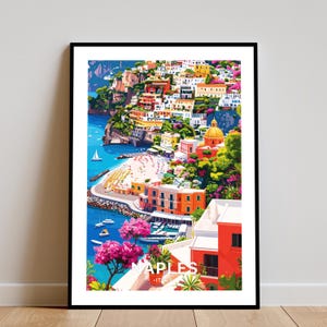 May include: A framed art print of Naples, Italy, featuring a colorful coastal town scene. The artwork depicts buildings in shades of yellow, orange, and white cascading down a hillside to the blue sea. The word "NAPLES" is visible in the lower portion of the print.