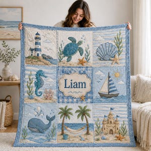 May include: A quilted blanket featuring a nautical theme with nine panels displaying a lighthouse, sea turtle, seashell, seahorse, the name Liam, a sailboat, a whale, a hammock between palm trees, and a sandcastle in shades of blue and tan.