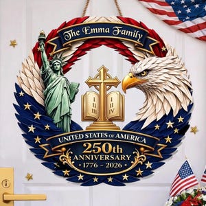 Op de afbeelding: Een patriottische krans met het Vrijheidsbeeld, een adelaar en een kruis met een open boek. De krans is versierd met rode, witte en blauwe elementen, en de tekst "The Emma Family" en "United States of America 250th Anniversary 1776-2026".