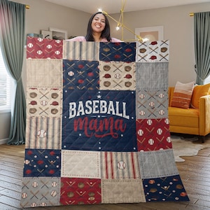 May include: A patchwork quilt featuring baseball-themed patterns in red, navy blue, and beige. The quilt has squares with baseballs, bats, gloves, and the text "Baseball Mama" in red script. The quilt is approximately 60 inches by 80 inches.