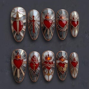 May include: A collection of ten artificial nails with religious motifs. Each nail showcases a unique design, such as hearts, crosses, swords, and flames, in red, gold, and white. The nails have a glossy finish and are displayed on a dark grey surface.