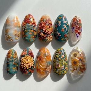 May include: A set of ten oval-shaped press-on nails featuring intricate 3D autumn-themed designs. The collection includes motifs of koi fish, bridges, chrysanthemums, sunflowers, and grapevines in a rich palette of orange, gold, teal, and brown.