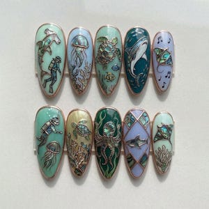 May include: A set of ten almond-shaped press-on nails featuring intricate ocean-themed designs. Each nail displays detailed illustrations of marine life including sharks, sea turtles, octopuses, jellyfish, and scuba divers, accented with iridescent shell inlays.
