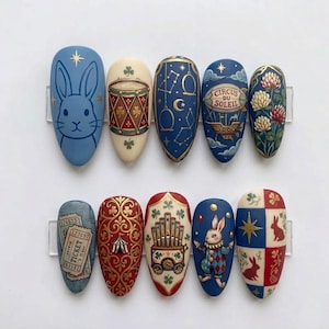 Puede incluir: Diez uñas pintadas con temática de circo. Los diseños incluyen un conejito azul, un tambor, constelaciones, un globo aerostático con el texto "Circus du Soleil", flores, un boleto, una carpa decorativa, un órgano, un conejo arlequín y conejos.