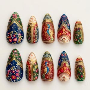 Peut inclure: Un ensemble de dix faux ongles en forme d'amande avec des motifs peints à la main. Les designs incluent des fleurs, des bordures géométriques et une illustration de paon, dans une palette riche de bleu marine, rouge profond, vert et doré.