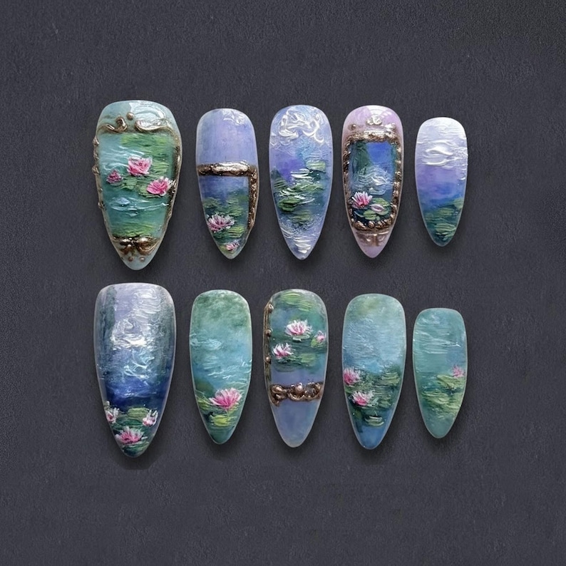 K&ouml;nnte beinhalten: Zehn k&uuml;nstliche Fingern&auml;gel, jeweils handbemalt mit einer Miniaturlandschaft mit Seerosen. Die Designs verwenden Blau-, Gr&uuml;n- und Rosat&ouml;ne, wobei einige N&auml;gel gold- oder bronzefarbene dekorative Rahmen aufweisen. Die N&auml;gel sind mandelf&ouml;rmig.