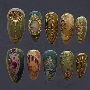 May include: A collection of ten intricately designed artificial nails. Each nail features unique artwork, including gold embellishments, floral patterns, and ornate designs in shades of green, gold, pink, and orange. The nails are oval-shaped and displayed against a dark background.