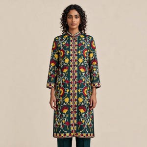 May include: A long-sleeved, knee-length dark green tunic featuring a high mandarin collar and a central button placket. The garment is decorated with intricate, symmetrical floral embroidery in vibrant shades of yellow, red, and white.